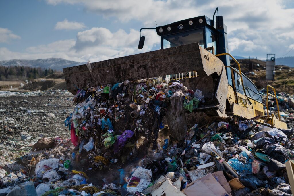 Garbage truck unloading waste on landfill, environmental concept