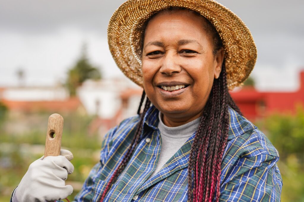Happy african senior woman harvesting at city community garden