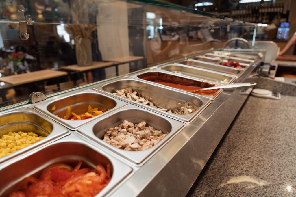 Various ingredients in metal containers placed in row in kitchen of traditional pizzeria